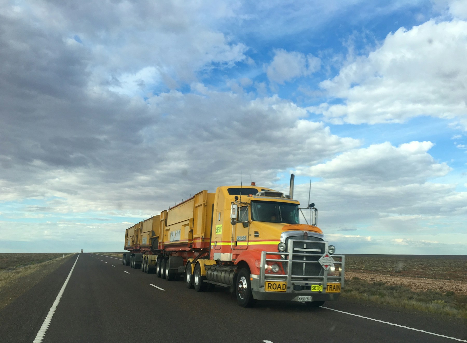 Australian road train carrying heavy mining equipment on a remote highway