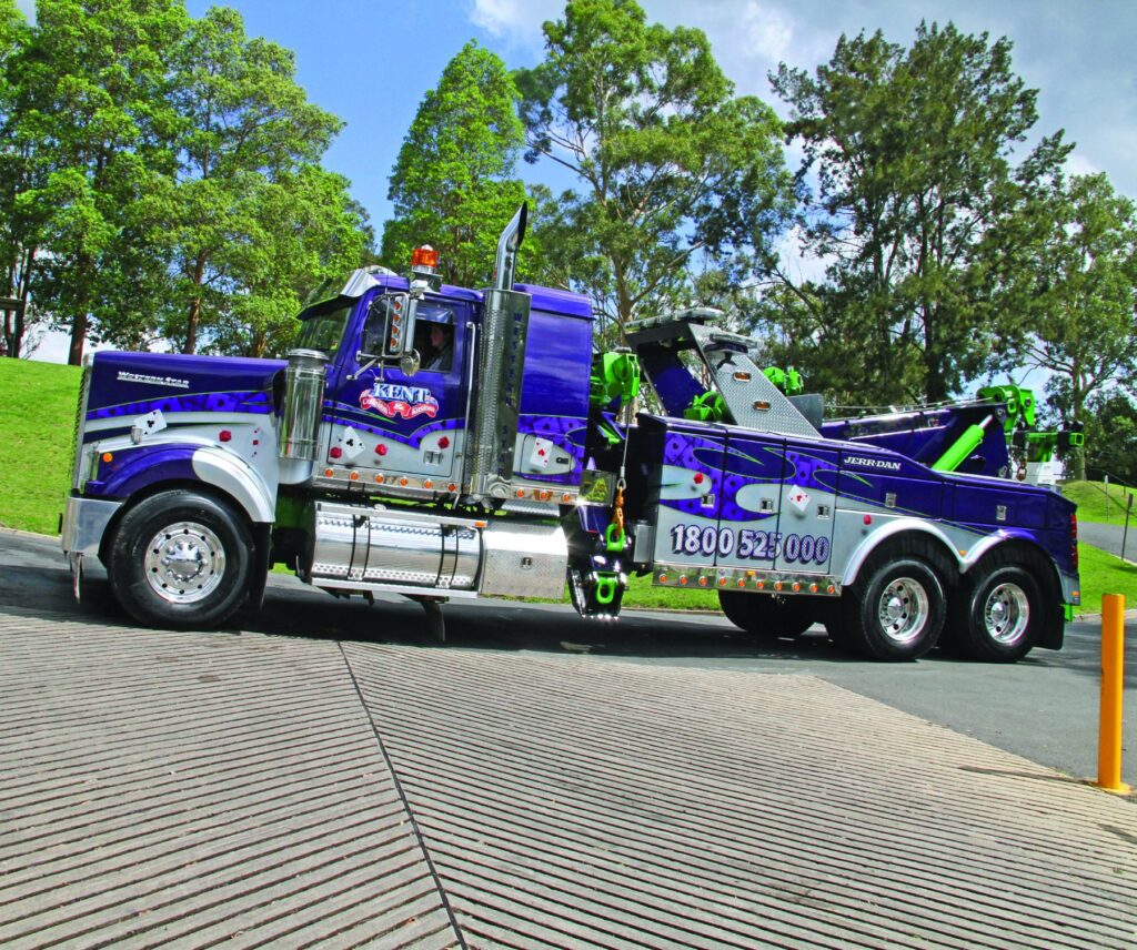 Kent Collision & Kustom’s purple and green Western Star heavy recovery truck parked beside trees