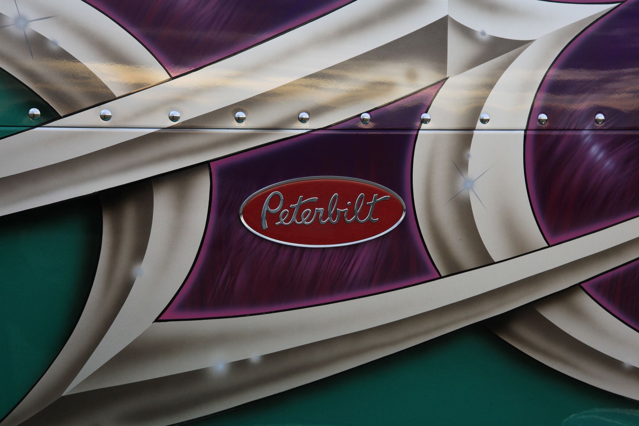 Close view of the custom Peterbilt badge and purple airbrushed paint on the Olivers’ truck