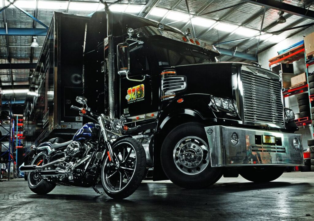 Black Harley-Davidson themed Freightliner Coronado parked beside a motorcycle in a workshop