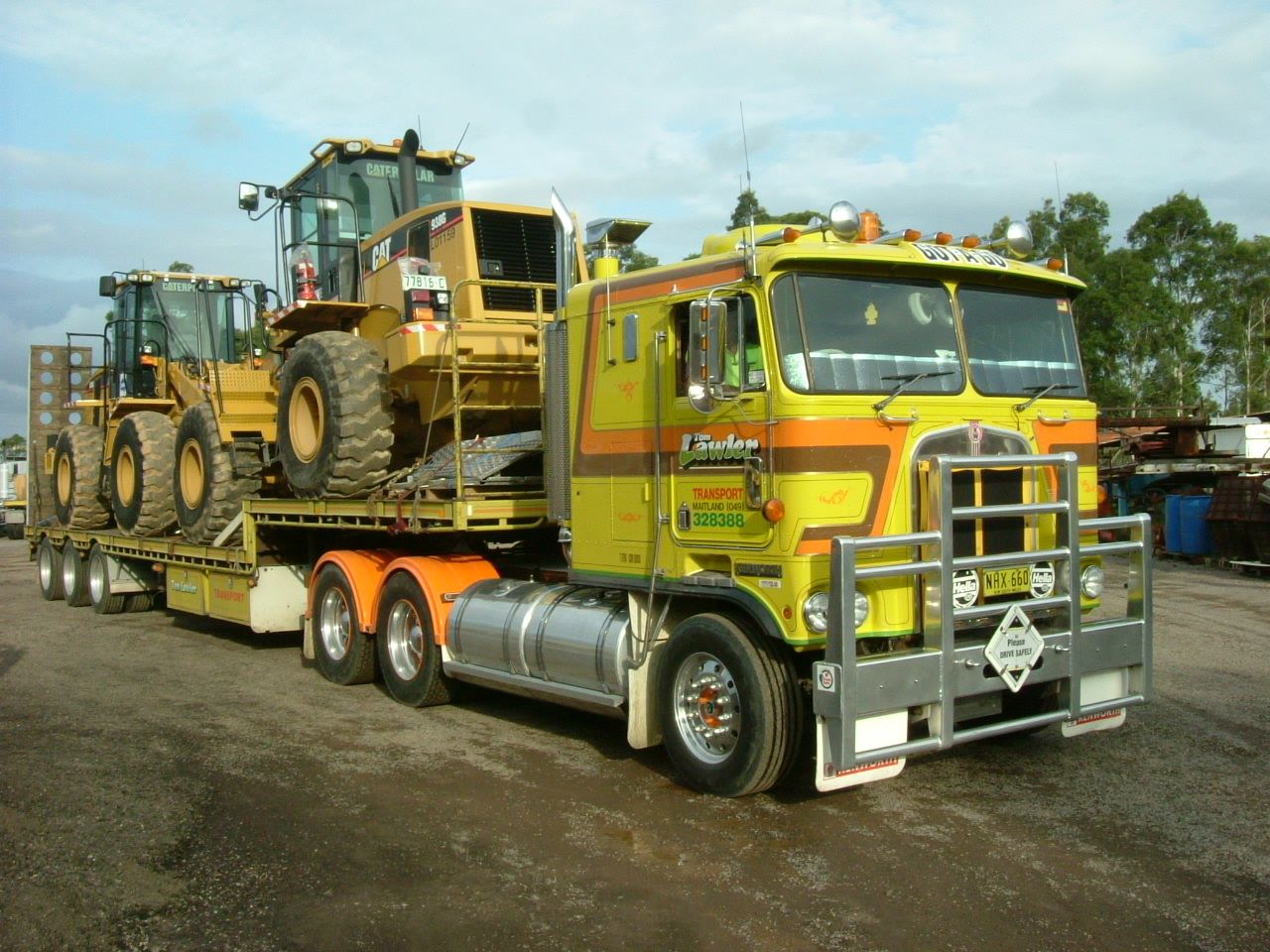 Yellow and orange 1983 Kenworth cab-over carrying machinery before Steve Lawler’s display restoration