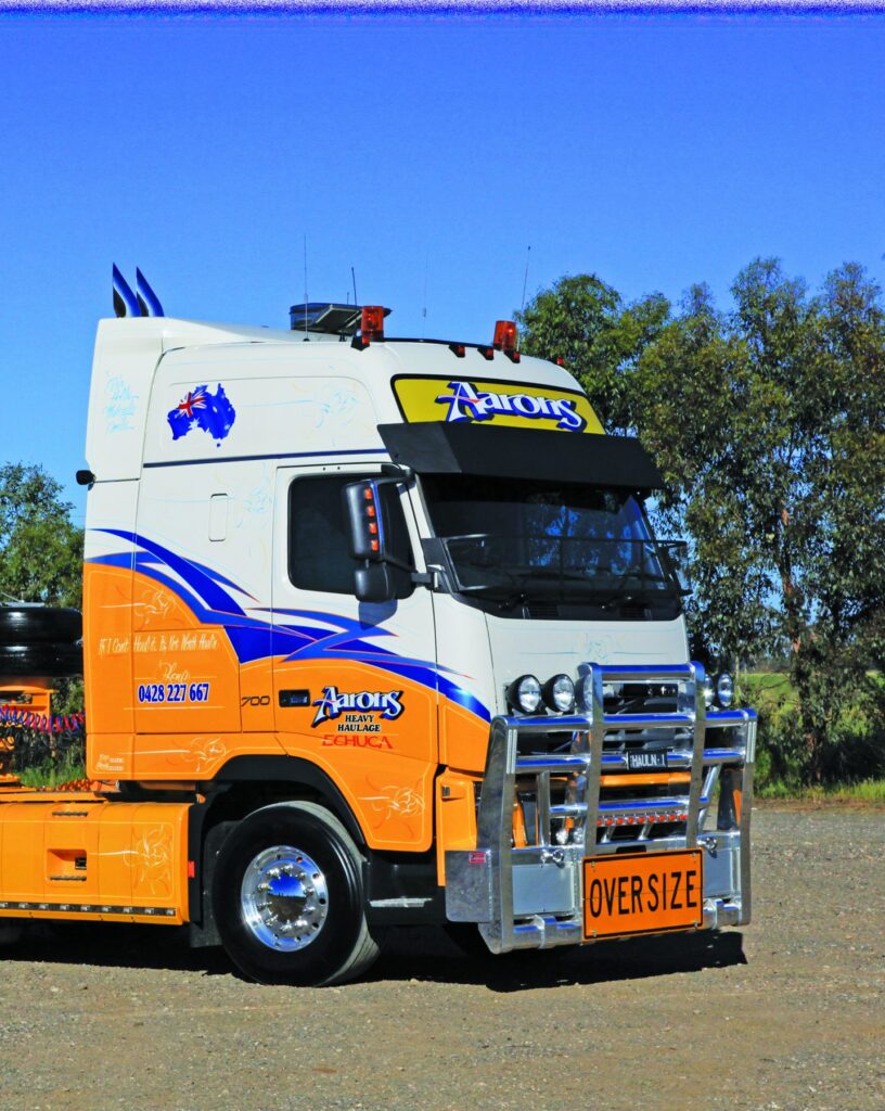 Aaron Pendlebury’s orange, white and blue Volvo FH16 heavy haulage truck with excavator on trailer