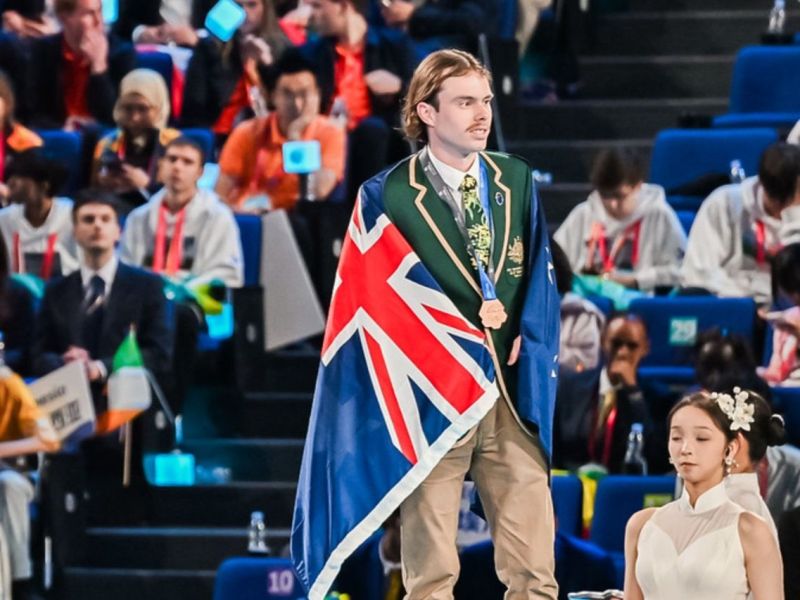Australian heavy-vehicle technician Lachlan Wright carries the Australian flag at WorldSkills Shanghai 2026.