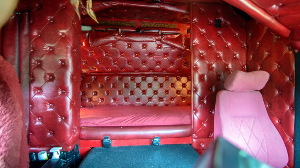 Bunk and buttoned red interior trim behind the seats of Trevor Smith’s Kenworth K100E.